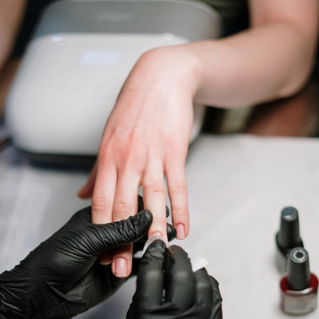 Close-up of a professional manicure with gel polish and black gloves in a salon.